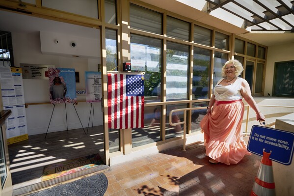 Volunteer Kristen Suszek also know as Poll Worker Barbie greets voters at the Connie Norman Transgender Empowerment Center polling station in the Hollywood section of Los Angeles, Tuesday, March 5, 2024. The center is the first transgender facility in the nation to host an election vote center. (AP Photo/Richard Vogel)