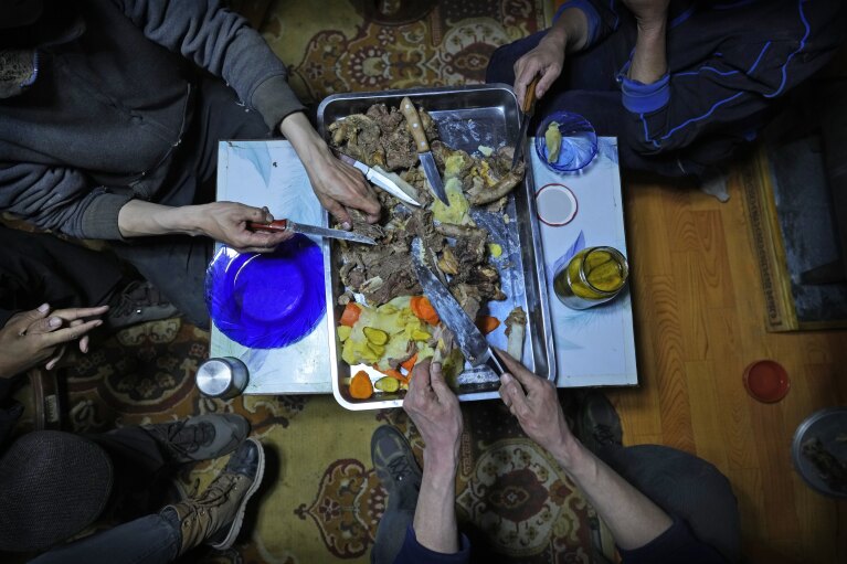 Herder Lkhaebum's family members share a supper of boiled meat in their ger, a portable, round tent insulated with sheepskin, upon their arrival at a new pasture in the Munkh-Khaan region of the Sukhbaatar district, in southeast Mongolia, Sunday, May 15, 2023. (AP Photo/Manish Swarup)