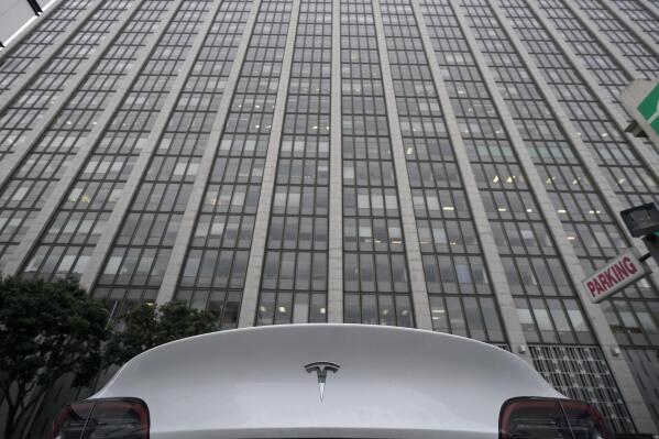 A Tesla car is parked in a lot across the street from a federal courthouse in San Francisco, Wednesday, Jan. 18, 2023. Elon Musk was depicted Wednesday as either a liar who callously jeopardized the savings of "regular people" or a well-intentioned visionary as attorneys delivered opening statements at a trial focused on a Tesla buyout that never happened. (AP Photo/Jeff Chiu)