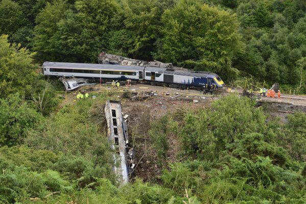 Emergency services inspect the scene near Stonehaven, Aberdeenshire, following the derailment of the ScotRail train, on Aug. 13, 2020. A British rail operator has pleaded guilty to health and safety failures for a train derailment three years ago in Scotland that killed three people and injured six others. Network Rail admitted in High Court in Aberdeen, Scotland, that it failed to ensure the safety of rail workers and passengers when heavy rains buried the track in gravel and caused the train to run off the tracks. (Ben Birchall/PA via AP)