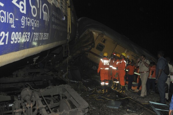 Rescuers and others stand after two passenger trains collided in Vizianagaram district, Andhra Pradesh state, India, Sunday, Oct.29, 2023. The crash happened when an incoming train slammed into a stationary train, leading to derailment of at least three rail cars. (AP Photo)