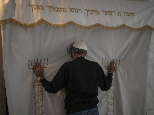 A Jewish congregant prays before the Torah ark at the Ohel Yaacov Synagogue in Marseille, southern France, Sunday, April 21, 2024. (AP Photo/Daniel Cole)