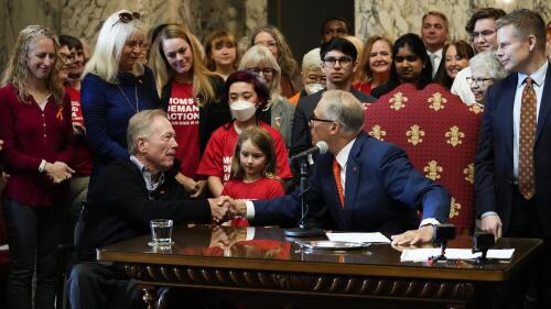 Washington Gov. Jay Inslee shakes the hands of Jim and Ann-Marie Parsons, in blue, whose daughter Carrie was killed in the 2017 Las Vegas shooting, after Inslee signed Senate Bill 5078, which ensures that firearms manufacturers and sellers will face liability if they fail to adopt and implement reasonable controls to prevent sales to dangerous individuals, Tuesday, April 25, 2023, at the Capitol in Olympia, Wash. (AP Photo/Lindsey Wasson)