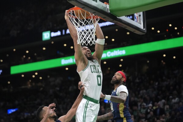 Boston Celtics forward Jayson Tatum (0) dunks the ball to score in front of New Orleans Pelicans forward Brandon Ingram, right, in the second half of an NBA basketball game, Monday, Jan. 29, 2024, in Boston. (AP Photo/Steven Senne)