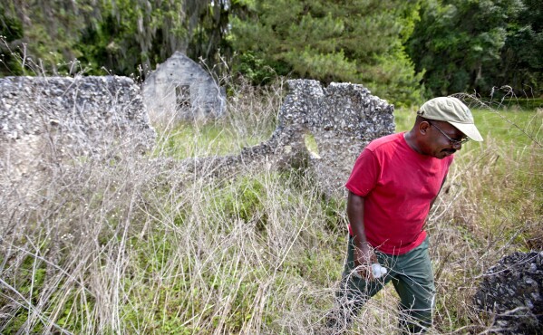 FILE - Ire Gene Grovner walks through remnants of the old slave's quarters, May 16, 2013, at the Chocolate Plantation where his ancestors lived some eight generations ago on Sapelo Island, Ga. One of the few remaining Gullah-Geechee communities in the U.S. is in another fight to hold onto land owned by residents' families since their ancestors were freed from slavery. The few dozen remaining residents of the tiny Hogg Hummock community on Georgia's Sapelo Island were stunned when they learned county officials may end zoning protections enacted nearly 30 years ago to protect the enclave from wealthy buyers and tax increases. (AP Photo/David Goldman, File)
