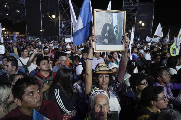 Supporters hold a photo or former Guatemalan President Juan Jose Arevalo as they listen to his son Bernardo, current presidential candidate with Seed Movement party, during his closing campaign rally at Constitution square in Guatemala City, Wednesday, Aug. 16, 2023. Arevalo faces rival and former first lady Sandra Torres of the UNE party in the Aug. 20 runoff election. (AP Photo/Moises Castillo)