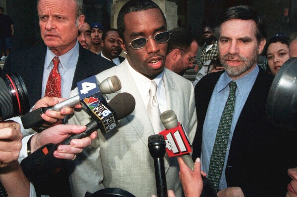 Rapper Sean "Puffy" Combs, center, speaks to the media outside of court in New York after his assault case was postponed on June 24, 1999. (AP Photo/Lynsey Addario, File)