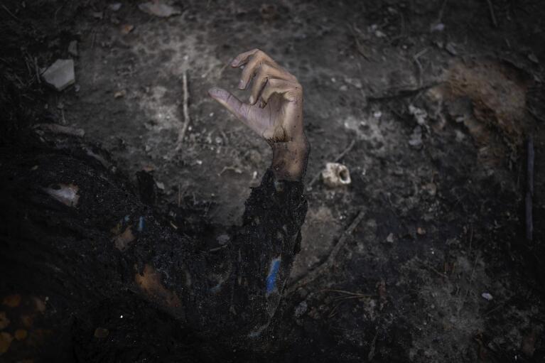 EDS NOTE: GRAPHIC CONTENT - The corpse of a man lies in the garden of a house in Bucha, on the outskirts of Kyiv, Ukraine, Sunday, April 3, 2022. Ukrainian troops found brutalized bodies and widespread destruction in the suburbs of Kyiv after Russian forces withdrew. (AP Photo/Rodrigo Abd)