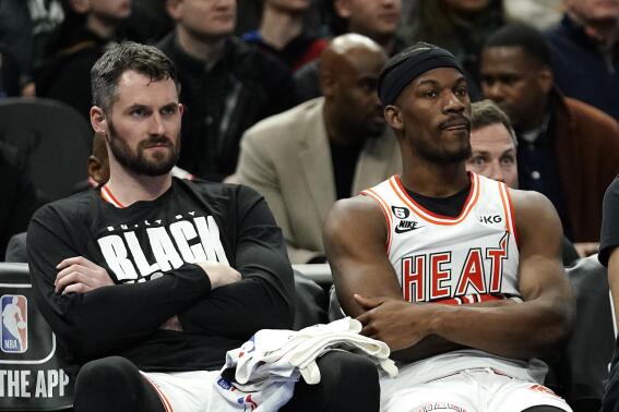 Miami Heat's Kevin Love, left, and Jimmy Butler, right, watch from the bench during the second half of an NBA basketball game against the Milwaukee Bucks Friday, Feb. 24, 2023, in Milwaukee. (AP Photo/Aaron Gash)