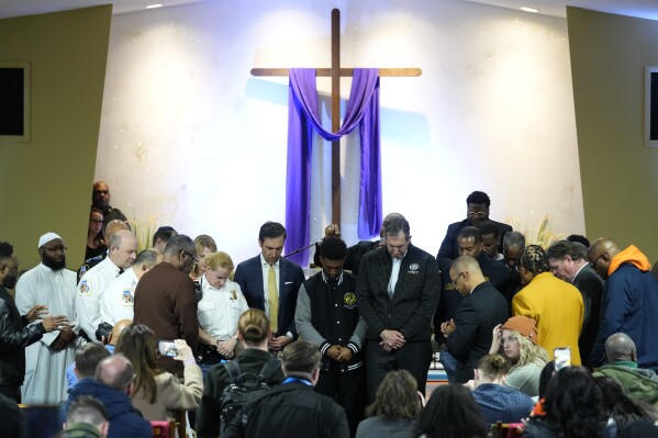 People pray for officials including Baltimore Mayor Brandon Scott, center, during a vigil near the scene where a container ship collided with a support on the Francis Scott Key Bridge, at Mount Olive Baptist Church in Dundalk, Md., Tuesday, March 26, 2024. (AP Photo/Matt Rourke)