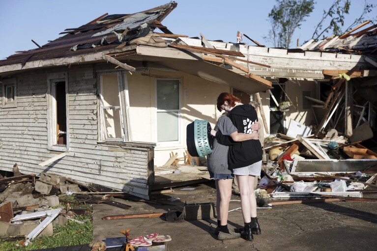 Joy King, left, and her granddaughter Crystal Maxey embrace in front of King's tornado-destroyed home on Tuesday, May 7, 2024, in Barnsdall, Oklahoma.The two search for King's cat and find it possible. They collected as many items as possible.  (Mike Simmons/Tulsa World, via AP)