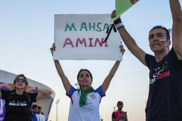A woman holds up a sign reading Mahsa Amini, a woman who died while in police custody in Iran at the age of 22, during a protest after the World Cup group B soccer match between Wales and Iran, at the Ahmad Bin Ali Stadium Al Rayyan, Qatar, Friday, Nov. 25, 2022. (AP Photo/Francisco Seco)