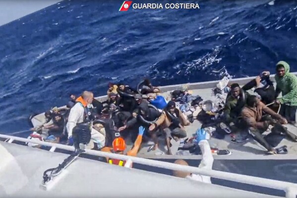 In this image taken from a video released by the Italian Coast Guard on Thursday, April 11, 2024, a boat with migrants is approached by a rescue operation off the island of Lampedusa in the Mediterranean Sea. The Italian Coast Guard rescued 22 people and recovered nine bodies on Thursday, April 10, 2024, after a smugglers' boat capsized in storm about 30 miles south of the island of Lampedusa. (Guardia Costiera via AP, HO)