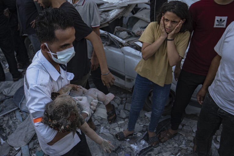 FILE - A Palestinian girl reacts as a child is carried from the rubble of a building after an airstrike in Khan Younis, Gaza Strip on Oct. 21, 2023. (AP Photo/Fatima Shbair, File)