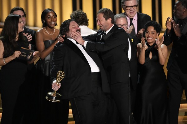 Matty Matheson, center, and Ebon Moss-Bachrach kiss as "The Bear" wins the award for outstanding comedy series during the 75th Primetime Emmy Awards on Monday, Jan. 15, 2024, at the Peacock Theater in Los Angeles. (AP Photo/Chris Pizzello)
