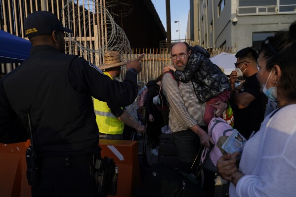 FILE - Ukrainian refugees speak with a United States Customs and Border Patrol official as they prepare to cross the border, Monday, April 4, 2022, in Tijuana, Mexico. The Biden administration on Friday, Aug. 18, 2023, announced a major expansion of temporary legal status for Ukrainians already living in the United States, granting a reprieve for those who fled Russia's invasion. (AP Photo/Gregory Bull, File)