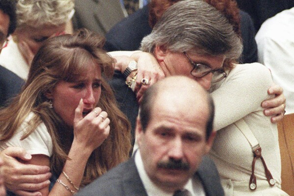 FILE - Fred Goldman, father of Ron Goldman, hugs his wife Patti, as his daughter, Kim, left, reacts during the reading of the not guilty verdicts in O.J. Simpson double-murder trial in Tuesday, Oct. 3,1995, in Los Angeles. Simpson was acquitted in the murders of Goldman and Simpson's ex-wife Nicole. Foreground is Los Angeles Police Detective Tom Lange, co-lead investigator in the case. Simpson, the decorated football superstar and Hollywood actor who was acquitted of charges he killed his former wife and her friend but later found liable in a separate civil trial, has died. He was 76. (Myung J. Chun/Los Angeles Daily News via AP, Pool, File)