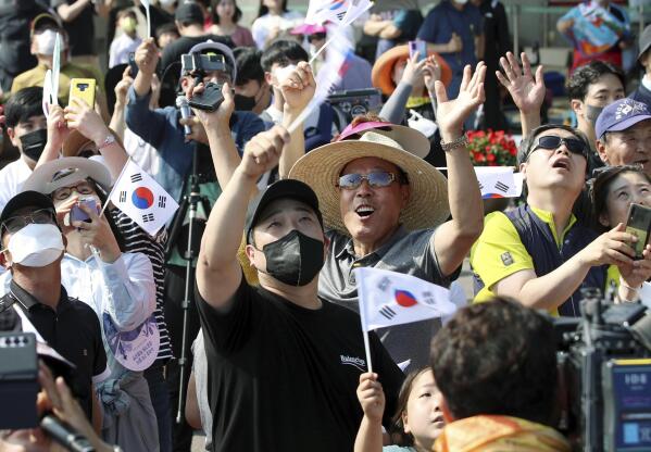People watch the Nuri rocket, the first domestically produced space rocket, taking off from the launch pad near the Naro Space Center in Goheung, South Korea, Tuesday, June 21, 2022. South Korea launched its first domestically built space rocket on Tuesday in the country's second attempt, months after its earlier liftoff failed to place a payload into orbit. (Chun Jung-in/Yonhap via AP)