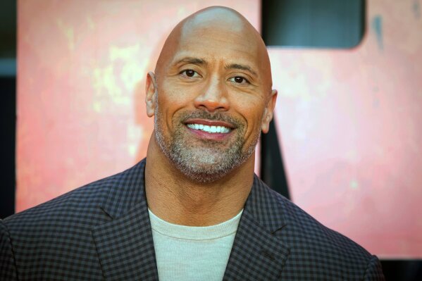 FILE - In this April 11, 2018, file photo, actor Dwayne Johnson poses for photographers at the premiere of the "Rampage," in London. Johnson will host and Justin Bieber, Miley Cyrus and Jennifer Hudson will perform on a globally broadcast concert calling on world leaders to make coronavirus tests and treatment available and equitable for all. The advocacy organization Global Citizen and the European Commission announced Monday, June 22, 2020 that Global Goal: Unite for Our Future — The Concert will air on June 27. (Photo by Vianney Le Caer/Invision/AP, File)
