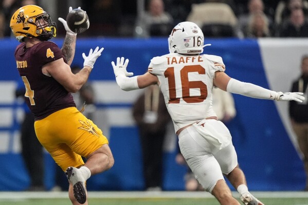 Arizona State running back Cam Skattebo (4) makes the catch against Texas defensive back Michael Taaffe (16) during the second half in the quarterfinals of a College Football Playoff game, Wednesday, Jan. 1, 2025, in Atlanta. Texas won 39-31 in two overtime periods. (AP Photo/John Bazemore)