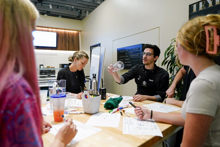Starbucks reusables business strategy senior manager Mary-Catherine Burton, left, takes notes as Tryer Lab partner Sam Farahani discusses design during a personal cup focus group at the Tryer Center at Starbucks headquarters, Wednesday, June 28, 2023, in Seattle. (AP Photo/Lindsey Wasson)