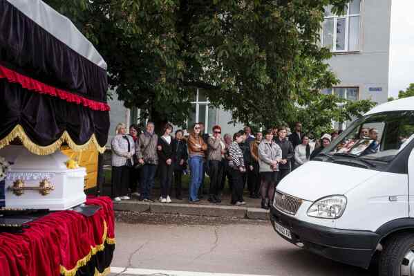 Local residents attand a funeral ceremony for Tamara Martyniuk, 8, Stanislav Martyniuk, 12, and Roman Martyniuk, 17, killed in a Russian strike on Sunday, in Korostyshiv, Zhytomyr region, Ukraine, Wednesday, May 28, 2025. (AP Photo/Evgeniy Maloletka)