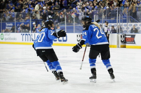 Toronto's Sarah Nurse (20) and Natalie Spooner (24) celebrate Spooner's goal against Boston during the third period of a PWHL hockey game Wednesday, March 20, 2024, in Toronto. (Cole Burston/The Canadian Press via AP)