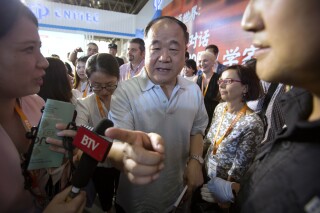 FILE - Chinese Literature Nobel Prize winner Mo Yan, center, leaves following a panel discussion at the Beijing International Book Fair in Beijing, Wednesday, Aug. 23, 2017. Mo Yan, one of China's most celebrated authors, who won the country's first Nobel Prize for literature and was once praised by top officials, is now at a center of a nationalist storm, indicating the shifting lines for freedom of expression under Chinese President Xi Jinping. (AP Photo/Mark Schiefelbein, File)