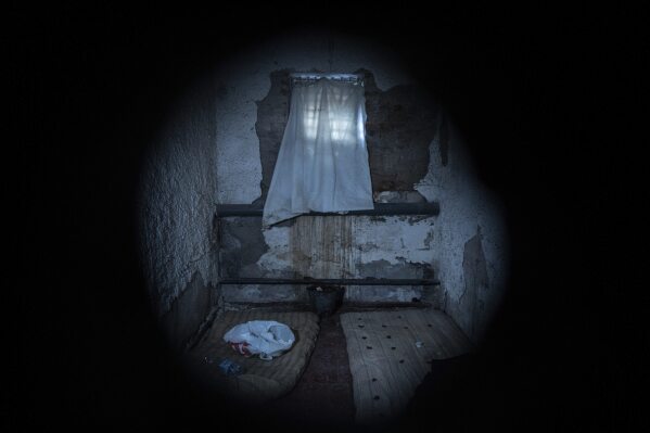 Seen through a peephole, a sheet covers the window of a jail cell in a police department in Izium, Ukraine, Thursday, Sept. 22, 2022. Ukrainian civilians said they were held and tortured at the site by Russian soldiers. (AP Photo/Evgeniy Maloletka)