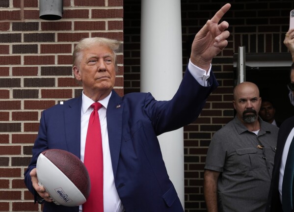 FILE - Former President Donald Trump holds a football before throwing it to the crowd during a visit to the Alpha Gamma Rho, agricultural fraternity, at Iowa State University before an NCAA college football game between Iowa State and Iowa, Sept. 9, 2023, in Ames, Iowa. Trump is set to attend South Carolina's biggest athletic event of the year, the Nov. 25 matchup between the University of South Carolina and Clemson University. (AP Photo/Charlie Neibergall, File)