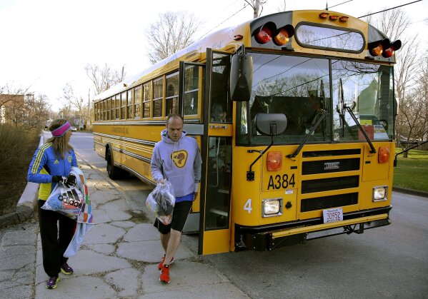 FILE - In this April 21, 2014, file photo, runners in the 118th Boston Marathon disembark a bus as they arrive near the start line in Hopkinton, Mass. Organizers of the marathon, postponed indefinitely because of the coronavirus pandemic, have launched a virtual Athletes' Village in 2020 to reproduce at least some of the camaraderie of the real thing. (AP Photo/Stephan Savoia, File)