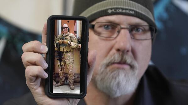 Matthew Butler, who spent 27 years in the Army, holds a 2014 photograph of himself during his last deployment in Kabul Afghanistan, on Wednesday, March 30, 2022, in Sandy, Utah. Butler is now one of the military veterans in several U.S. states who are helping convince conservative lawmakers to take cautious steps toward allowing the therapeutic use of hallucinogenic mushrooms and other psychedelic drugs. The therapeutic used of so-called magic mushrooms and other psychedelic drugs is making inroads in several U.S. states, including some with conservative leaders, as new research points to their therapeutic value and military veterans who have used them to treat post-traumatic stress disorder become advocates. (AP Photo/Rick Bowmer)