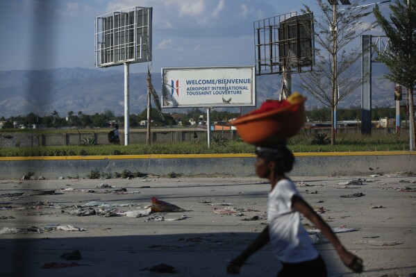 A pedestrian walks past the international airport in Port-au-Prince, Haiti, Monday, March 4, 2024. Gang members exchanged gunfire with police and soldiers around the airport in the latest of a series of attacks on government sites, which includes a mass escape from the country’s two biggest prisons. (AP Photo/Odelyn Joseph)