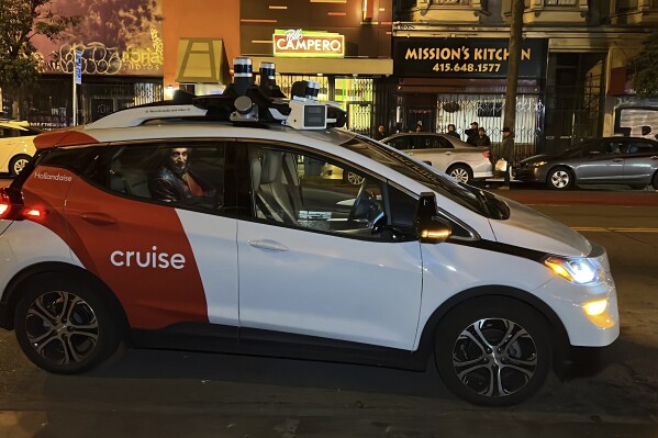 FILE - Associated Press reporter Michael Liedtke sits in the back of a Cruise driverless taxi that picked him up in San Francisco's Mission District, Feb. 15, 2023. California's Department of Motor Vehicles on Tuesday, Oct. 24, immediately suspended operation of Cruise's driverless robotaxis in San Francisco, citing public safety after one of its cars ran over a person fatally struck by a vehicle driven by a human. (AP Photo/Terry Chea, File)