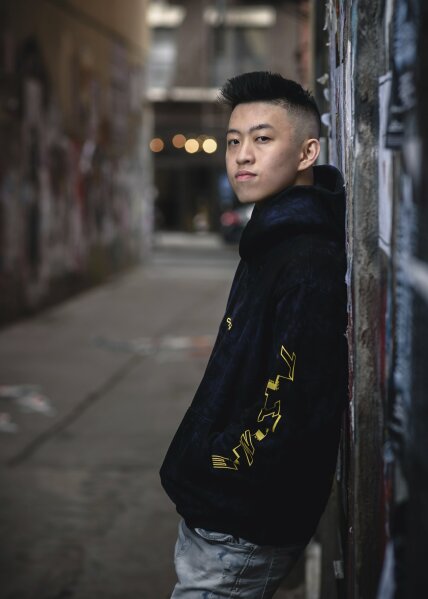 an asian boy in a black denim jacket posing like a naughty boy
