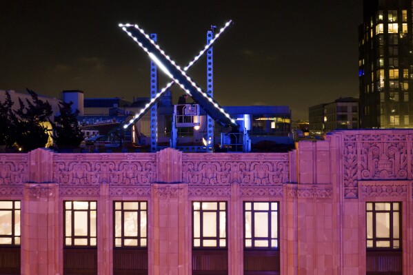 Trabajadores instalan un cartel de "X" en el techo de la sede de la empresa (antes Twitter) en el centro de San Francisco, 28 de julio de 2023. (AP Foto/Noah Berger, Archivo)