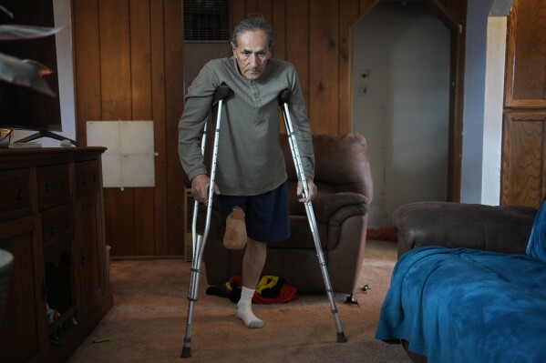 Blas Sanchez makes his way through a room in his home, Friday, Jan. 26, 2024, in Winslow, Ariz. Sanchez's leg was mutilated while working near the chicken manure chute as a prison laborer at Hickman's Family Farms in 2015 in Tonopah, Ariz. (AP Photo/John Locher)