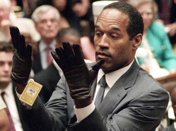 FILE - In this June 21, 1995 file photo, OJ Simpson raises his hands to jurors after donning a new pair of gloves similar to the infamous bloody gloves during his double-murder trial in Los Angeles.  Simpson, the award-winning soccer superstar and Hollywood actor who was acquitted of murdering his ex-wife and her boyfriend but later found guilty in a separate civil trial, has died.  He was 76. (Vince Bucci/Pool Photo via AP, File)