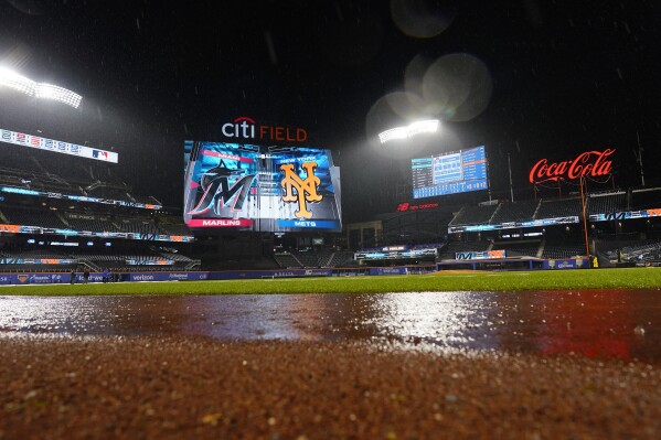 Grounds crew members work on the field during a rain delay of a baseball game between the New York Mets and the Miami Marlins early Friday, Sept. 29, 2023, in New York. (AP Photo/Frank Franklin II)