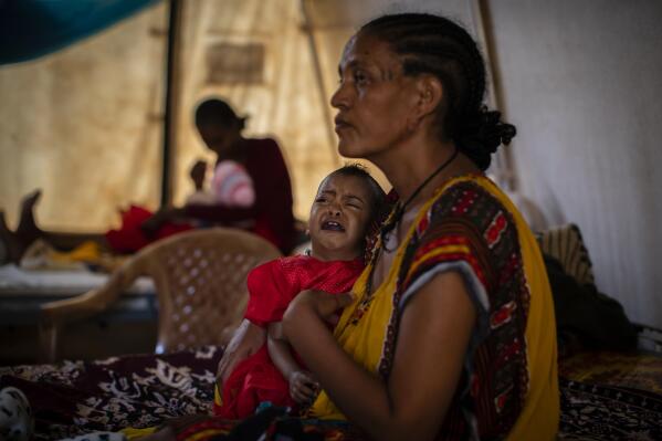 In this Tuesday, May 11, 2021 photo, Roman Kidanemariam, 35, holds her malnourished daughter, Merkab Ataklti, 22 months old, in the treatment tent of a medical clinic in the town of Abi Adi, in the Tigray region of northern Ethiopia. As the United States warns that up to 900,000 people in Tigray face famine conditions in the world’s worst hunger crisis in a decade, little is known about vast areas of Tigray that have been under the control of combatants from all sides since November 2020. With blocked roads and ongoing fighting, humanitarian groups have been left without access. (AP Photo/Ben Curtis)