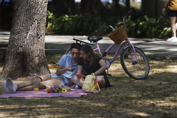 FILE - A couple sit on a blanket in Chapultepec Park, in Mexico City, March 4, 2023. The poverty rate in Mexico has declined from 49.9% of the population in 2018 to 43.5% in 2022, according to a study published Thursday, Aug. 10, 2023, by the country’s poverty analysis agency. (AP Photo/Marco Ugarte, File)