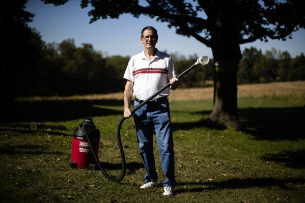 In this Thursday, Sept. 19, 2019, photo, Jim Wood poses for a photograph with his wet/dry vac he uses to deal with the swarms of lanternflies that have been attacking his trees in Allentown, Pa. The spotted lanternfly has emerged as a serious pest since the federal government confirmed its arrival in southeastern Pennsylvania five years ago this week. (AP Photo/Matt Rourke)