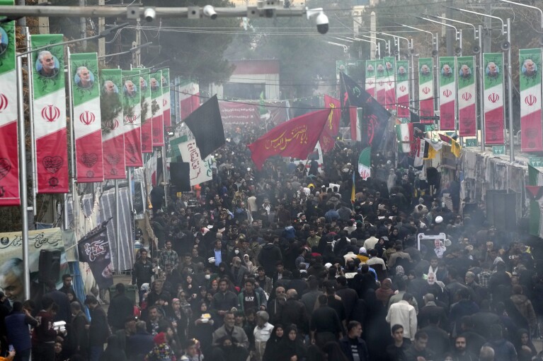 People walk down a street toward the grave of late Iranian Revolutionary Guard Gen. Qassem Soleimani in the city of Kerman, about 510 miles (820 kilometers) southeast of the Iranian capital, Tehran, on Thursday, Jan. 4, 2024.  Investigators believe the suicide bomber may have carried out the attack in memory of an Iranian general killed in a 2020 US drone strike, state media reported on Thursday, as Iran reeled from its biggest mass-casualty attack in decades. Struggling and the broader Middle East remains on the sidelines.  (AP Photo/Vahid Salemi)