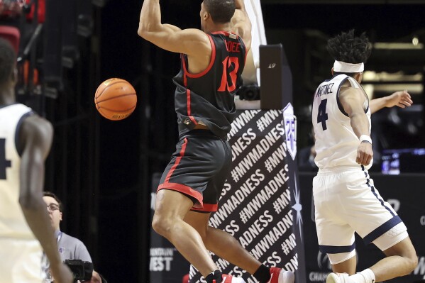 San Diego State forward Jaedon LeDee (13) dunks against Utah State during the first half of an NCAA college basketball game in the semifinals of the Mountain West Conference men's tournament Friday, March 15, 2024, in Las Vegas. (AP Photo/Ronda Churchill)