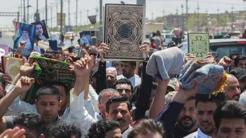 Supporters of Shiite cleric Muqtada al-Sadr lift the Quran, the holy book of Muslims, in response to the burning of a copy of the Quran in Sweden, during open-air prayers on Friday in Basra, Iraq, Friday, June 30, 2023. AP Photo/Nabil al-Jurani)