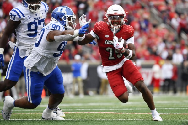 Louisville running back Jawhar Jordan (25) attempts to avoid the defense of Duke defensive tackle DeWayne Carter (90) during the first half of an NCAA college football game in Louisville, Ky., Saturday, Oct. 28, 2023. (AP Photo/Timothy D. Easley)