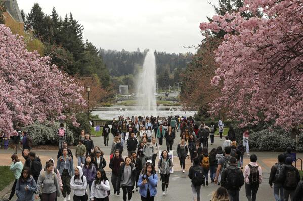 FILE - In this April 3, 2019, file photo, students walk between classes on the University of Washington campus in Seattle. Five Black police officers claiming racism at the University of Washington have filed claims for $8 million in damages. They say they were routinely insulted and demeaned by co-workers and supervisors. KOMO-TV reported Tuesday, June 22, 2021, that the officers say they were disciplined and denied promotions because of their race. (AP Photo/Ted S. Warren, File)