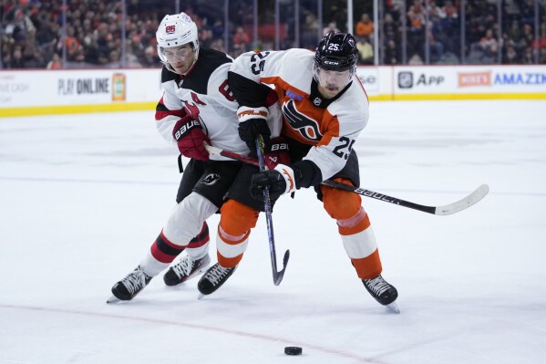 Philadelphia Flyers' Ryan Poehling, right, and New Jersey Devils' Jack Hughes battle for the puck during the second period of an NHL hockey game, Thursday, Nov. 30, 2023, in Philadelphia. (AP Photo/Matt Slocum)