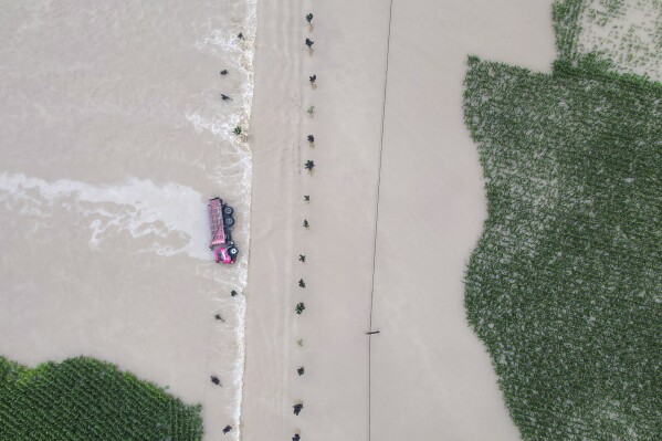In this aerial photo released by Xinhua News Agency, a truck turned on its side is seen as flood waters flowing across roads and fields in Kaiyuan Town of Shulan in northeastern China's Jilin Province on Friday, Aug. 4, 2023. Northeastern China continued to be pelted by rain on Saturday, as authorities reported more deaths and missing people and evacuated thousands in the wake of Typhoon Doksuri. (Yan Linyun/Xinhua via AP)