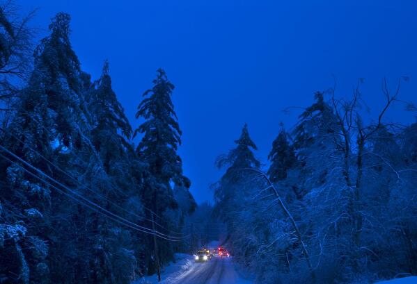 FILE - Utility crews prepare to work on power lines at dusk on in Litchfield, Maine, Dec. 26, 2013, where many had been without electricity since a storm earlier in the week. Weather disasters fueled by climate change now roll across the U.S. year-round, battering the nation's aging electric grid. (AP Photo/Robert F. Bukaty, File)